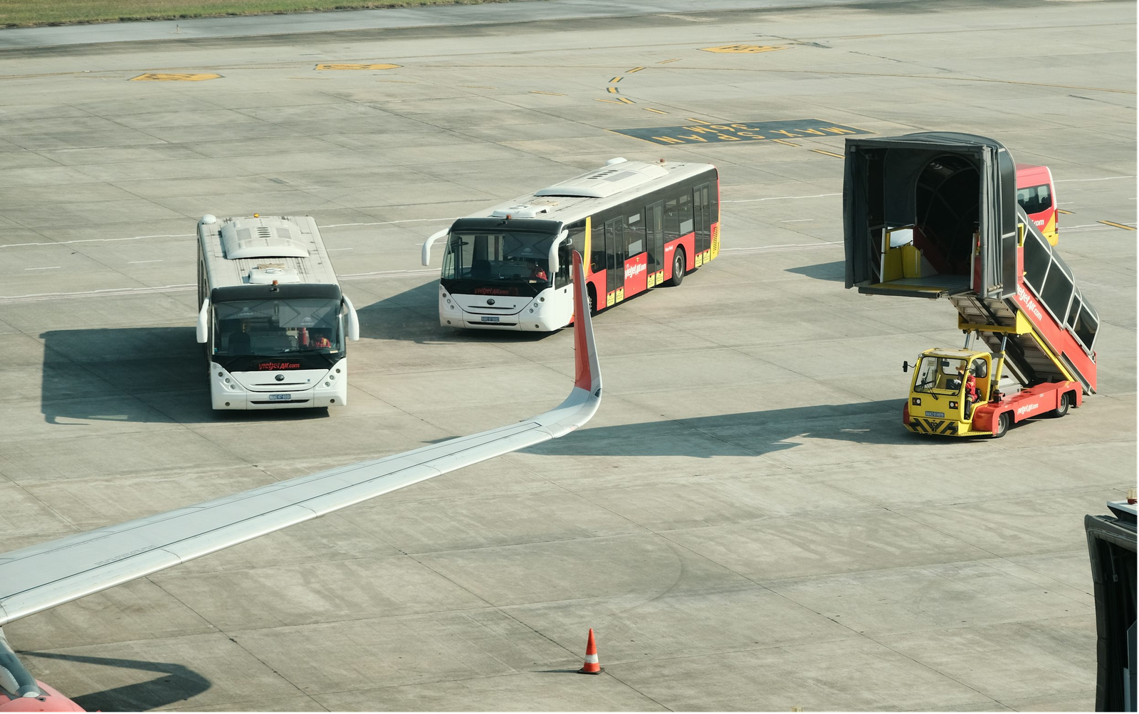 Airport tarmac with shuttle buses and a baggage loader.