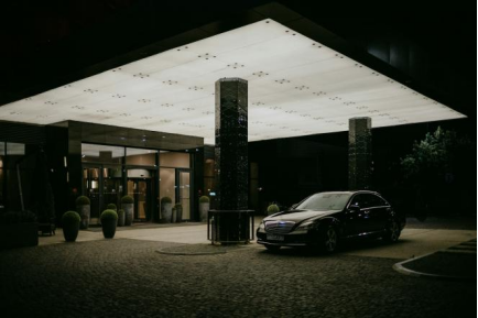 Exterior view of a hotel entrance at night with a luxury car parked nearby